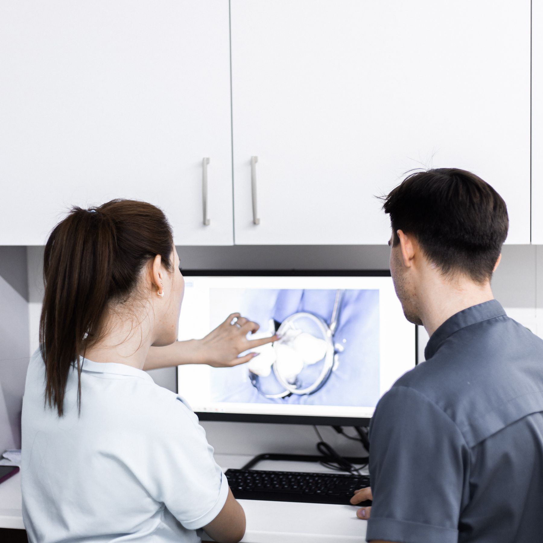 Dental clinicians reviewing digital tooth imaging at a modern clinical workstation